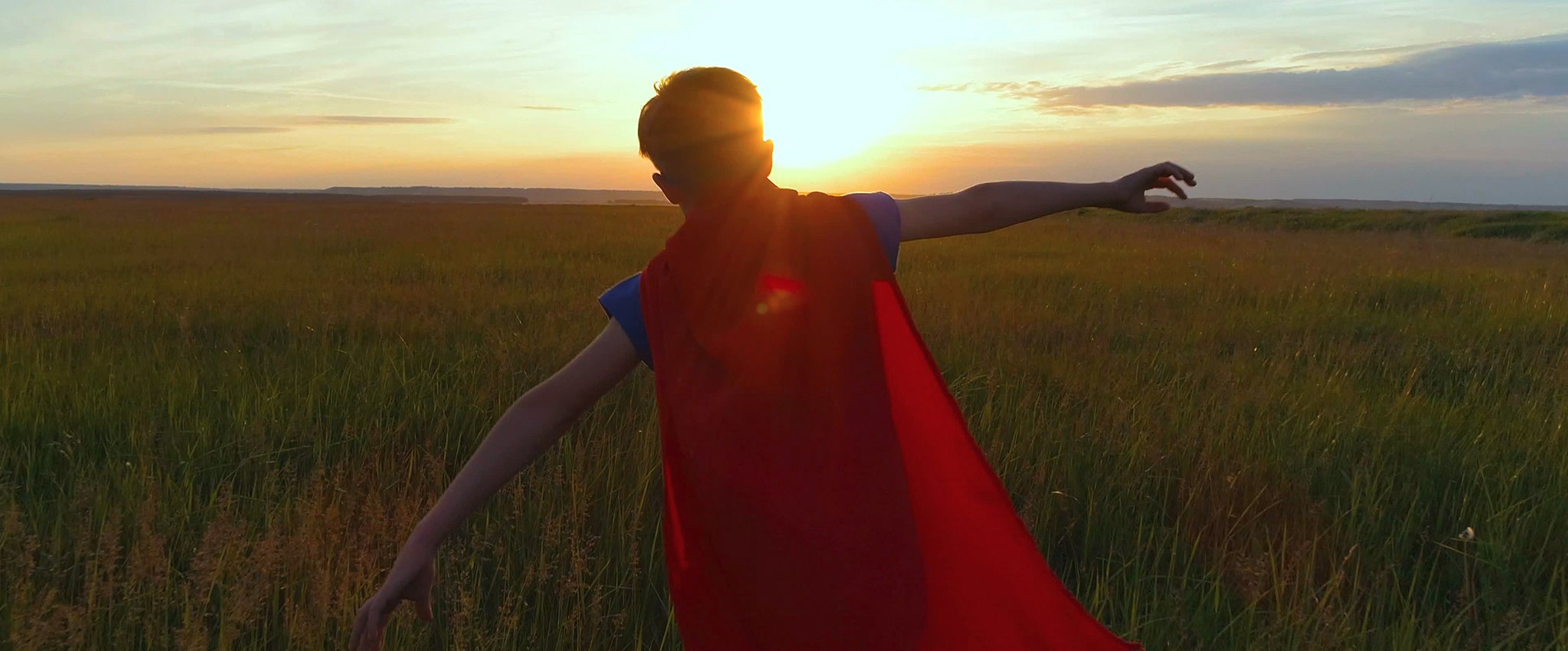 Image Credit: "A boy in a superman costume runs across the green field at sunset" by megaalex11590