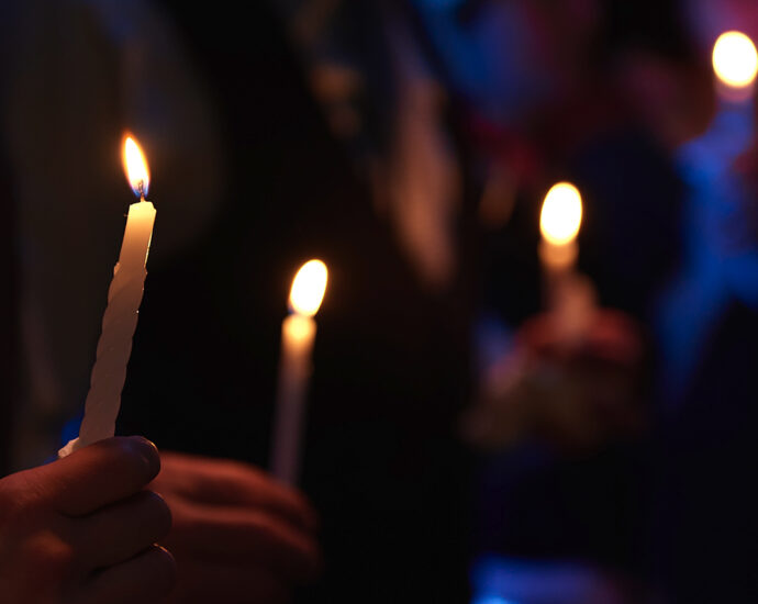People holding lit candles in a night scene.