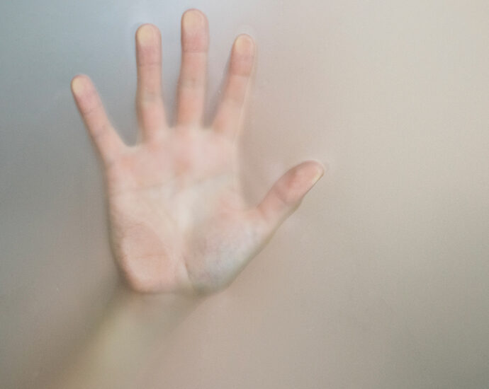 A woman's hand pressed against the glass, reaching out from within the fog.