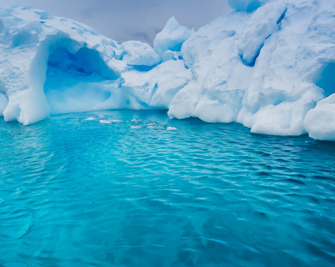 The hidden underside of a large glacier is visible through the turquoise waters of Antarctica.