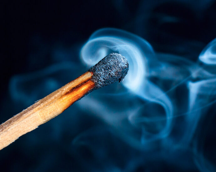 Billows of smoke still flow from the head of a thoroughly burnt wooden match.