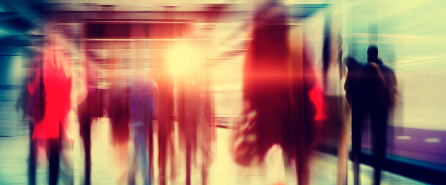 A blurred and stylized image of business people walking through a city subway at rush hour.