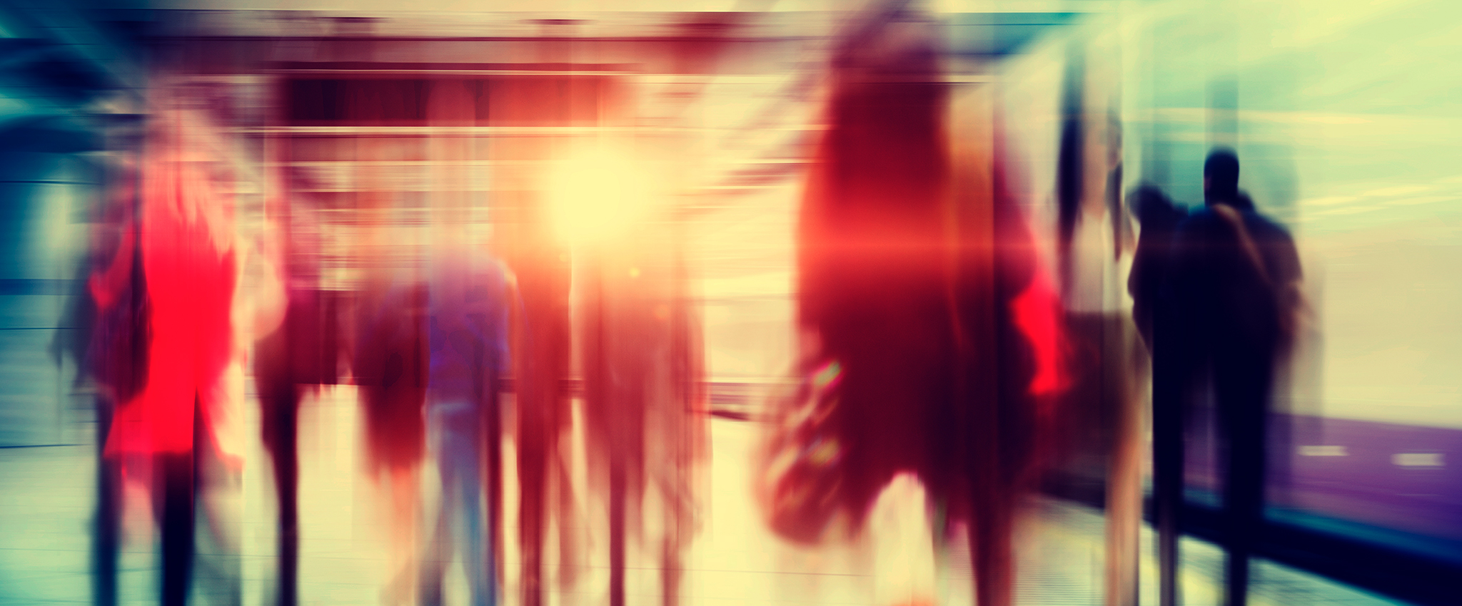 A blurred and stylized image of business people walking through a city subway at rush hour.