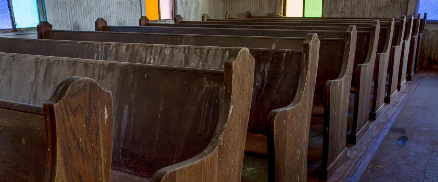 Worn wooden pews and colorful windows line the center aisle of a little old church. Taken at First Methodist Church of Jermyn. NOTE: this church was built in 1910. In 1968, it was designated as a Texas Historic Landmark.