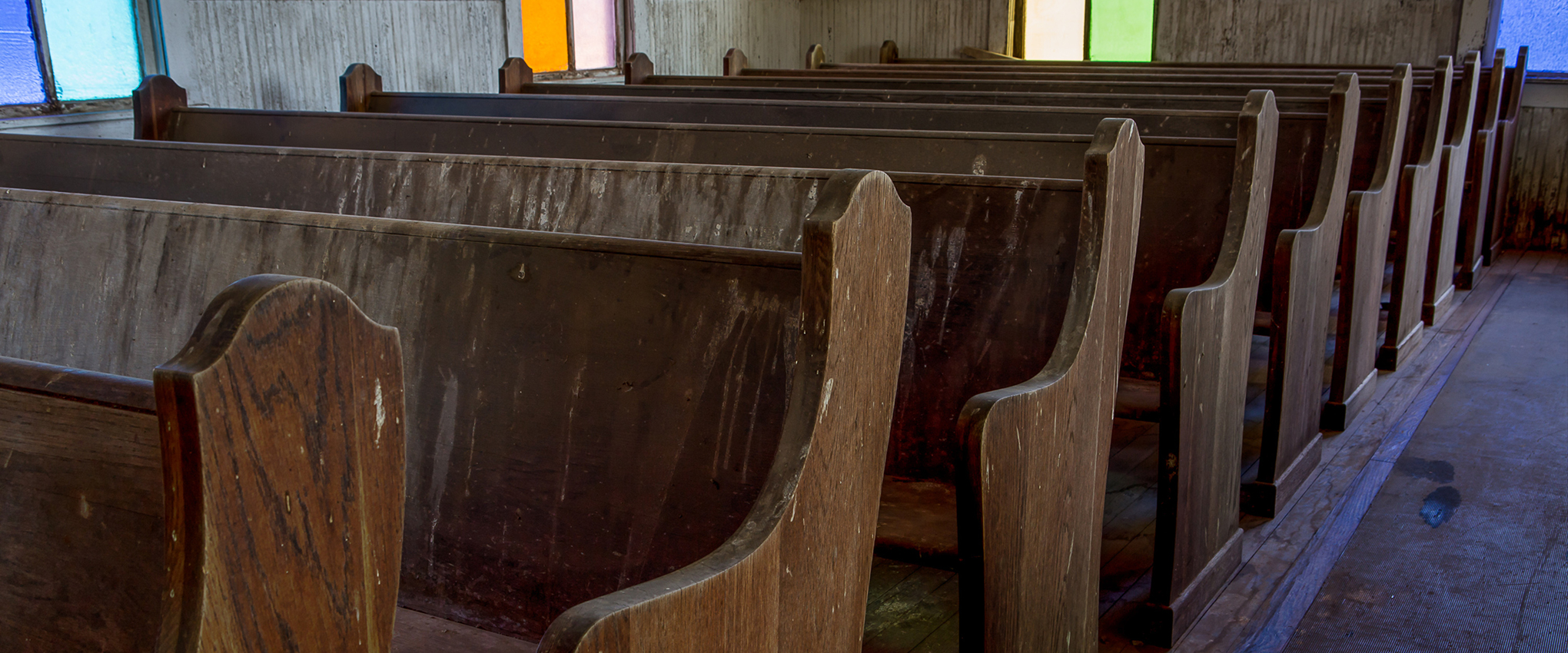 Worn wooden pews and colorful windows line the center aisle of a little old church. Taken at First Methodist Church of Jermyn. NOTE: this church was built in 1910. In 1968, it was designated as a Texas Historic Landmark.