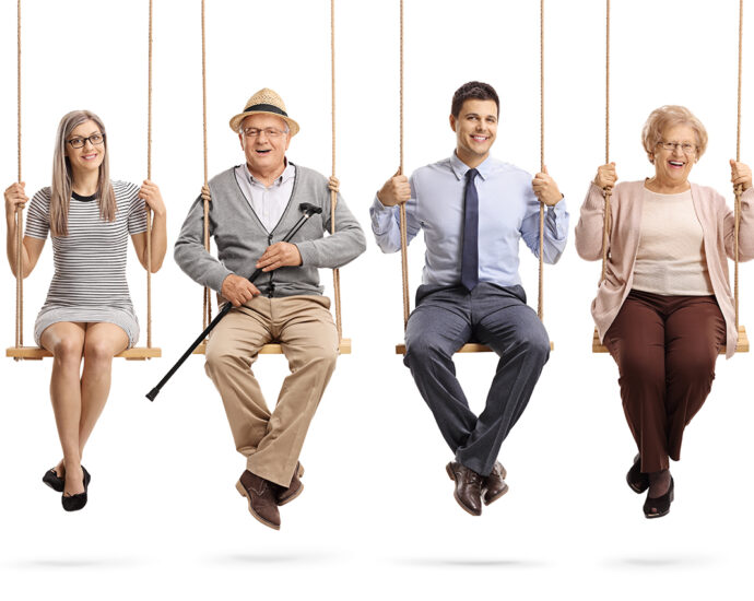 Children, young people, and seniors—8 in all—sit on swings and smile.
