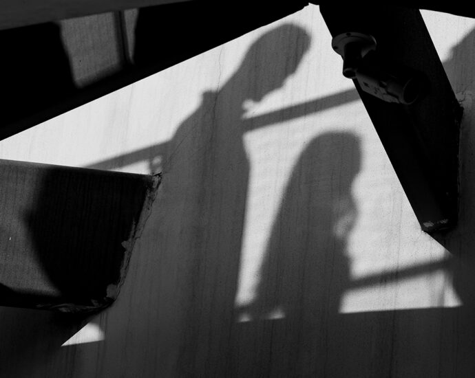 Shadows on a wall, cast by people walking by. Abstract silhouettes amongst large wooden beams.