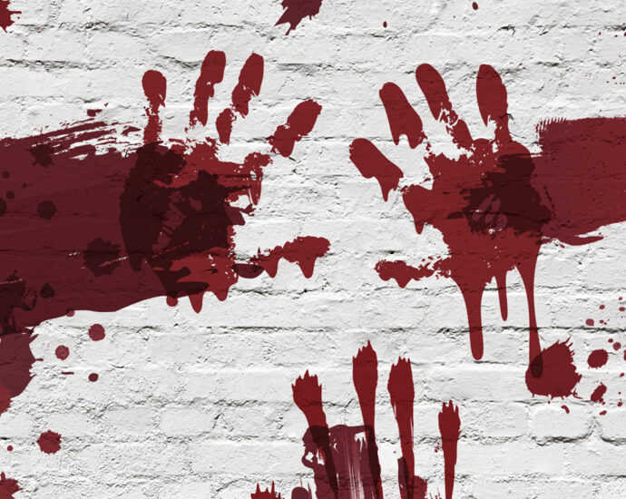 A white, painted brick wall, with handprints, smears, and splatters of red across it.