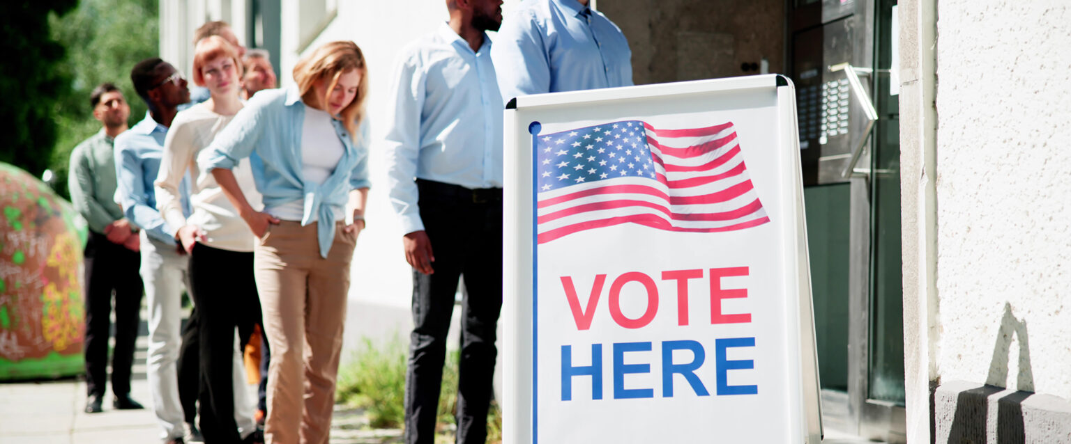 A diverse group of people wait in line to vote at a local polling location.