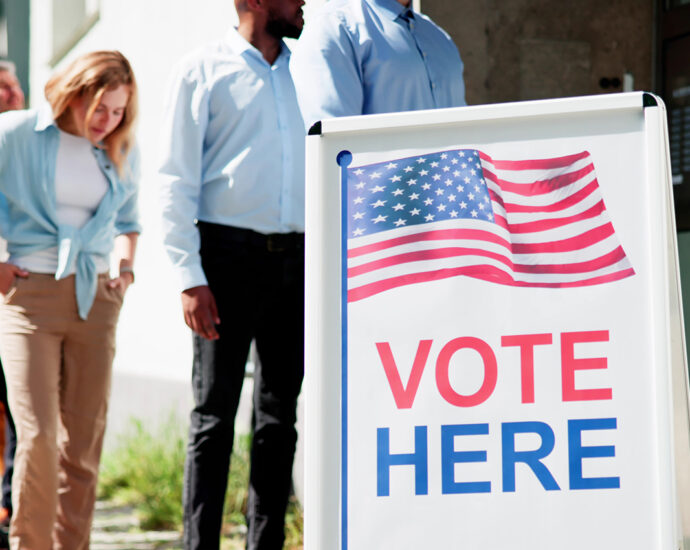 A diverse group of people wait in line to vote at a local polling location.
