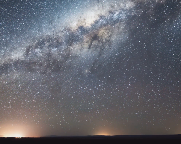 The glow of a distant city beneath a desert sky full of stars.