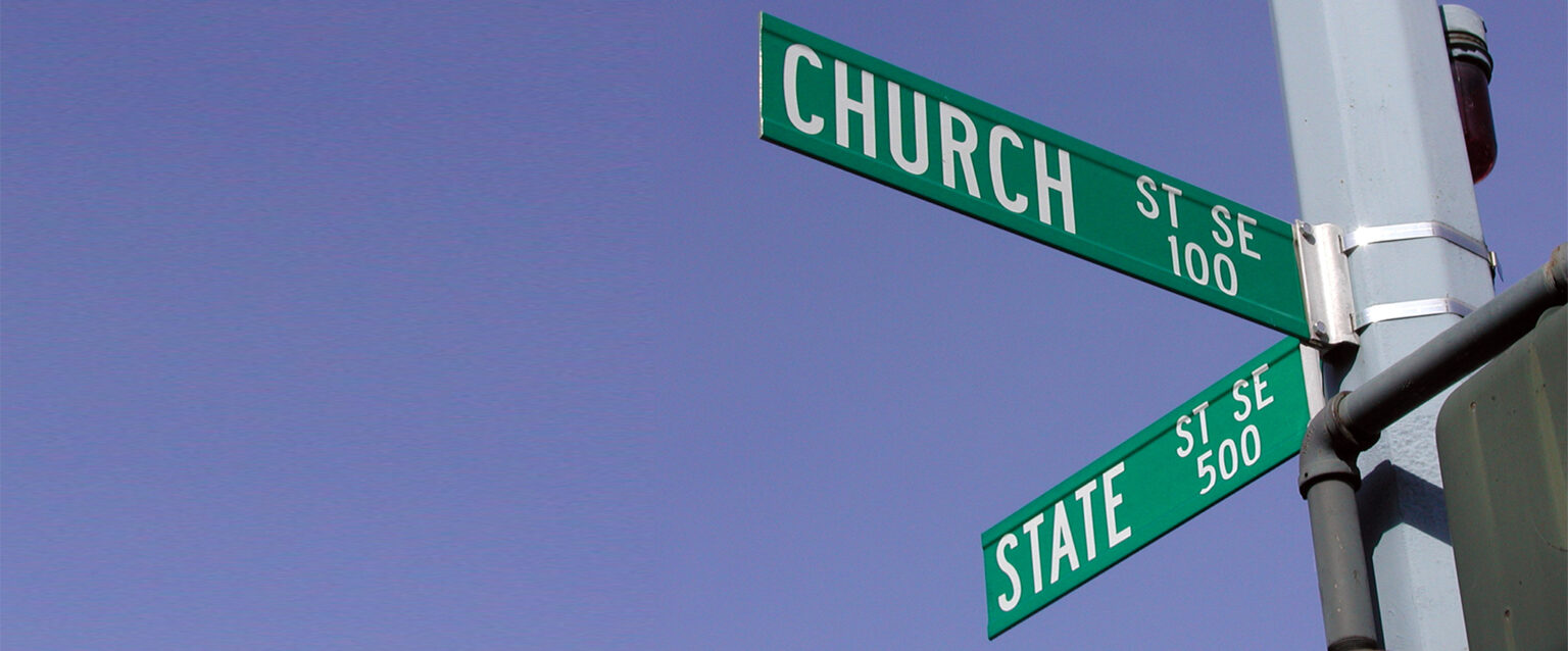 Street signs backed by a clear blue sky, at the intersection of Church and State Streets in Salem, Oregon.
